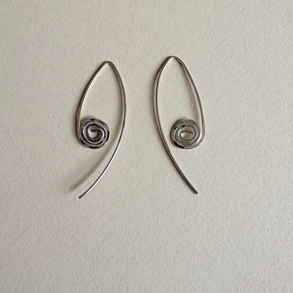 Close product detail of a pair of spiral drop earrings.
