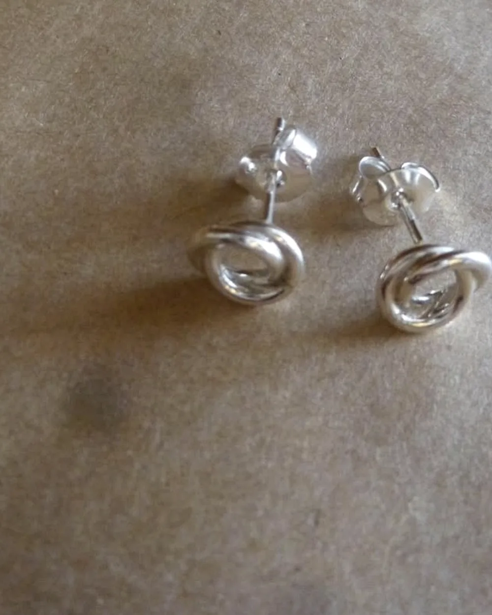 Pair of small spiral stud earrings on a neutral grey surface.